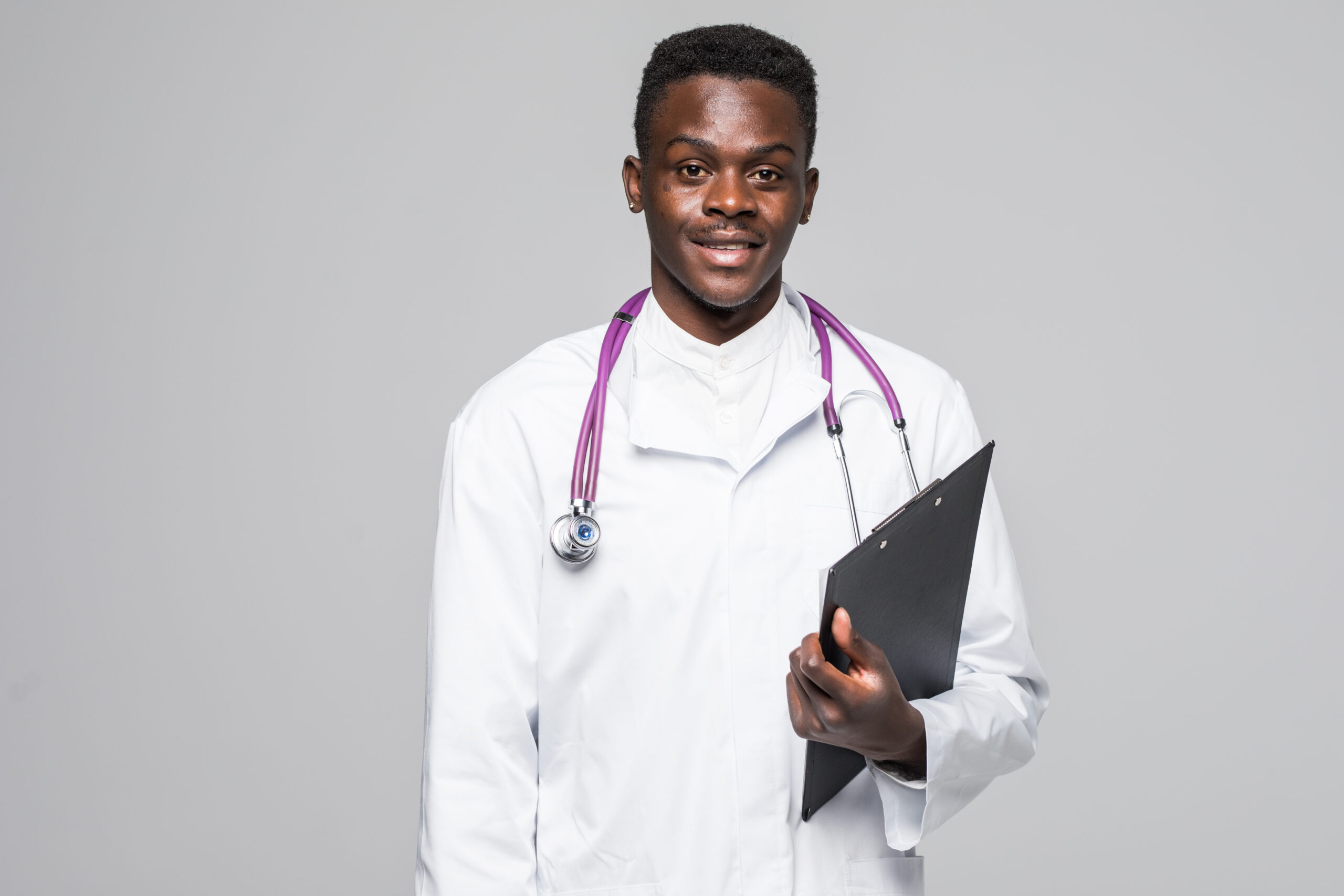 Friendly Afro-American doctor holding a clipboard and smiling at the camera